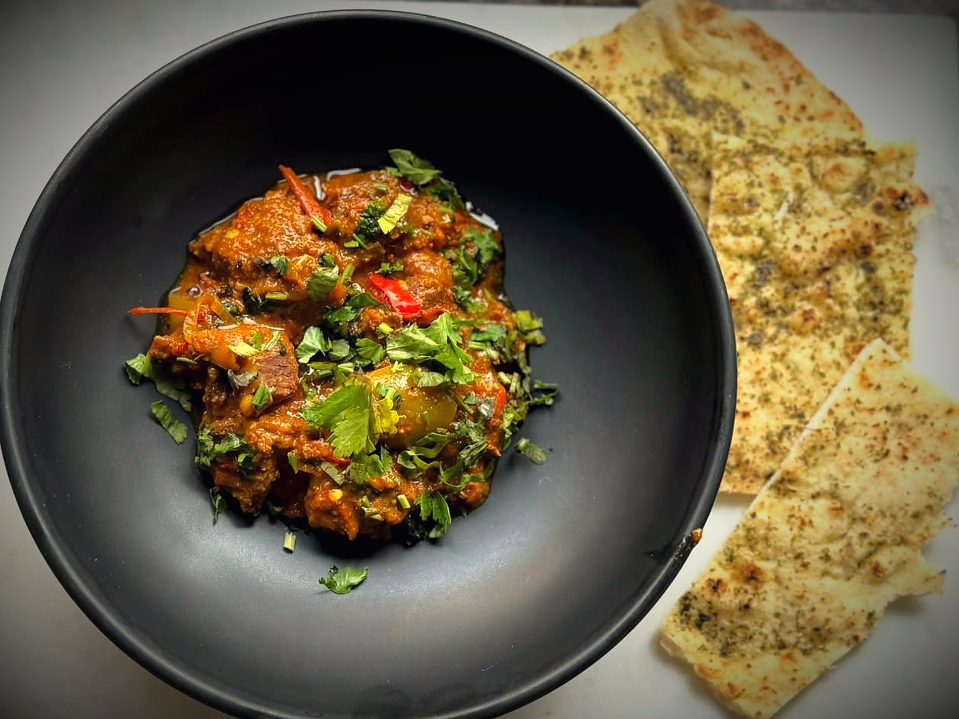 Lamb curry with naan on a dark plate